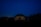 A geodesic dome structure is illuminated from within against a night sky, surrounded by dark silhouettes of trees. A telescope stands on the right side, hinting at stargazing activities.