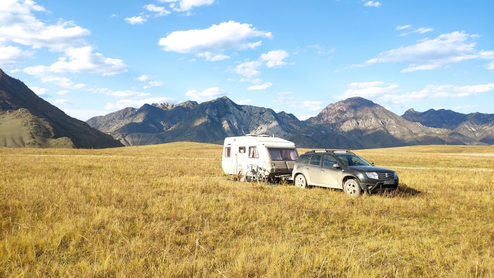 black suv on brown grass field near mountain under blue sky during daytime