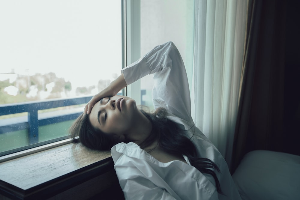 woman in white dress shirt lying on bed