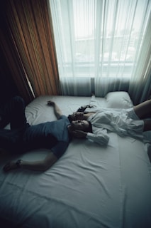 man in blue shirt lying on bed lying with his partner on a bed after reading erotic literature 