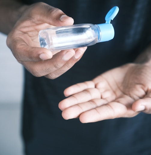 person holding clear glass bottle with blue lid