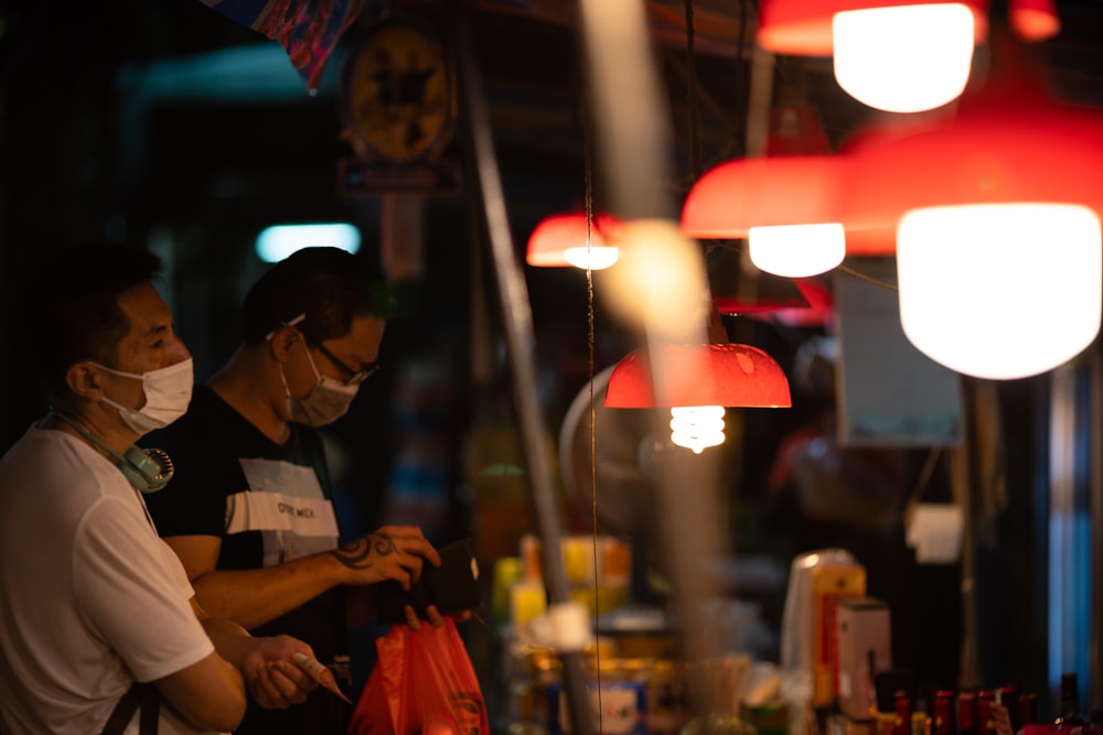 man in white and black stripe polo shirt standing near store during night time