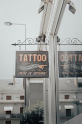 a tattoo parlor sign hanging from the side of a building