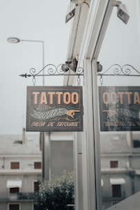 a tattoo parlor sign hanging from the side of a building