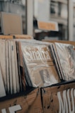 Numerous vinyl records are displayed in a store, with some covers prominently featuring the word 'Sinatra'. The records are neatly arranged in a row, and there are musical notes and letters decorating the storage boxes.