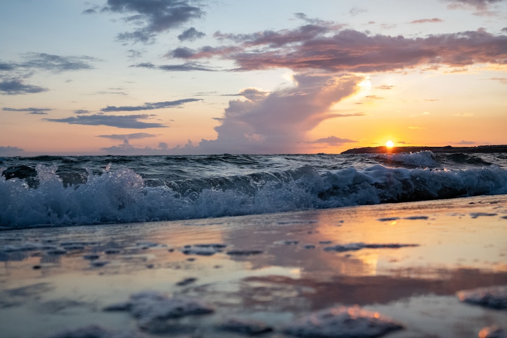 ocean waves crashing on shore during sunset