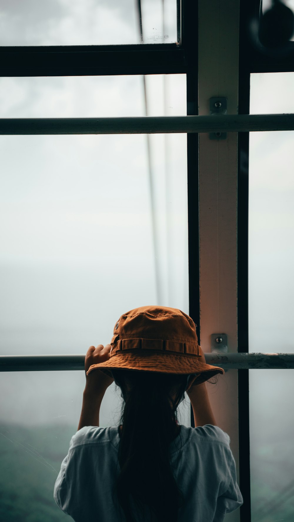 a woman wearing a hat looking out a window