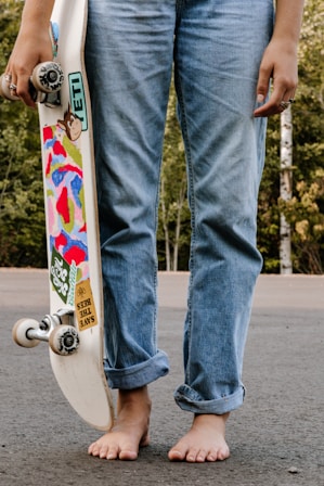 adolescent en jean pieds nus avec un skateboard