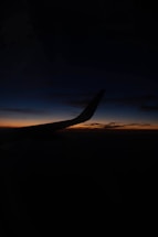 airplane wing over the clouds during sunset