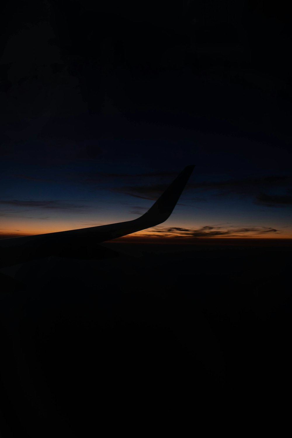 airplane wing over the clouds during sunset