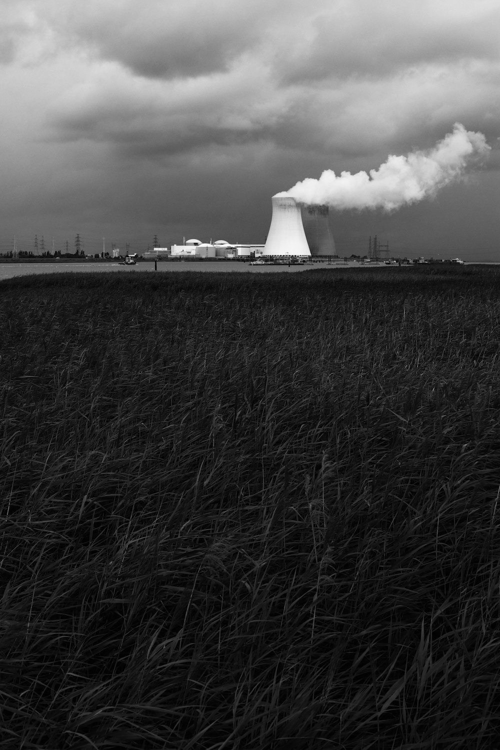 grayscale photo of factory under cloudy sky