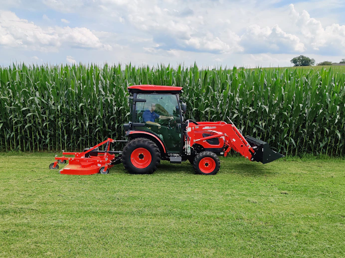 red tractor on green grass field under white clouds during daytime