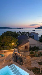 Evening view of a tiny house lit softly beside a sparkling pool.