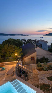 Evening view of a tiny house lit softly beside a sparkling pool.