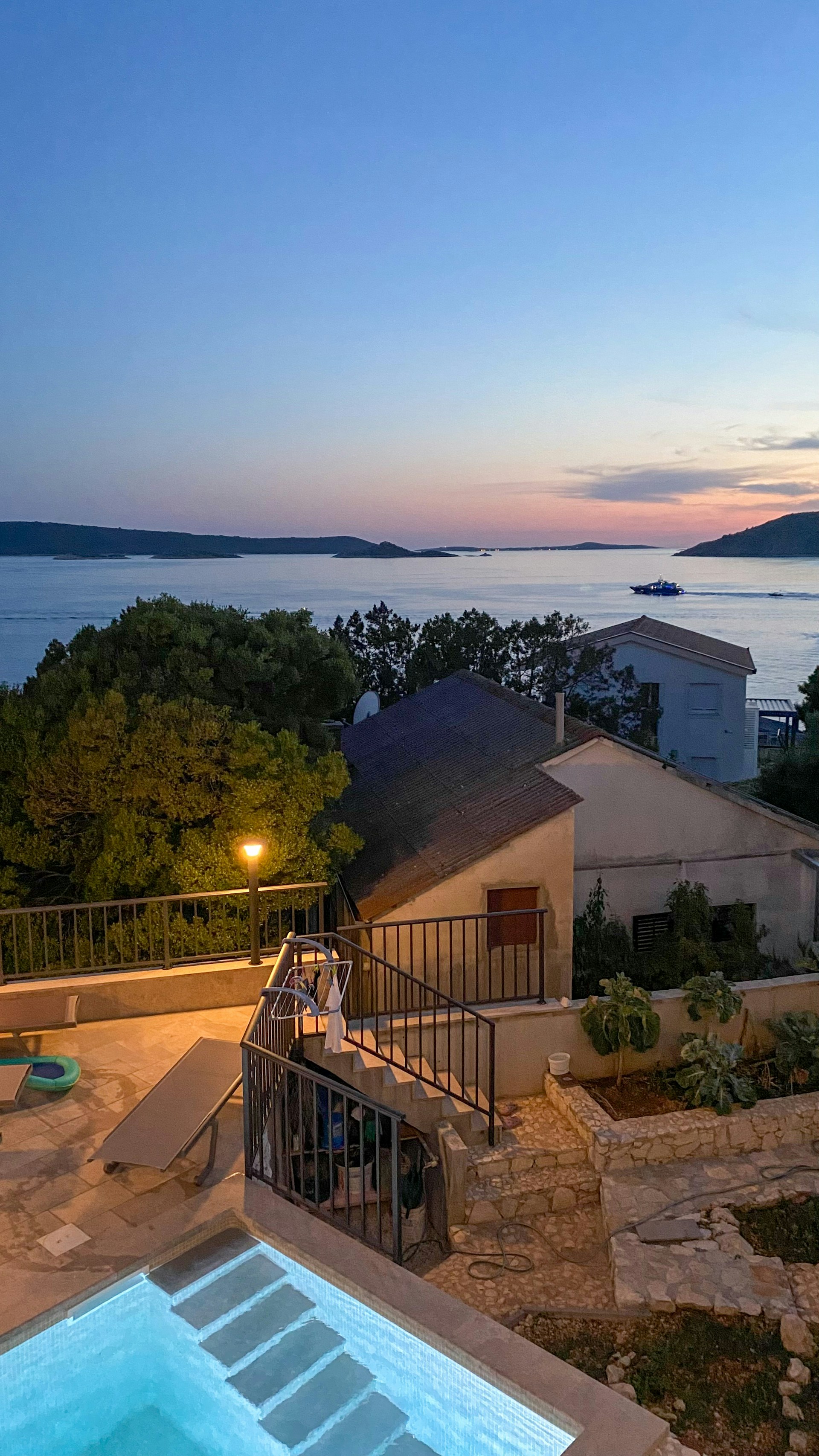 A serene villa terrace overlooking a calm sea at sunset with soft natural light.