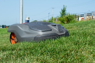 Technician monitoring robotic lawn equipment on a sunny day