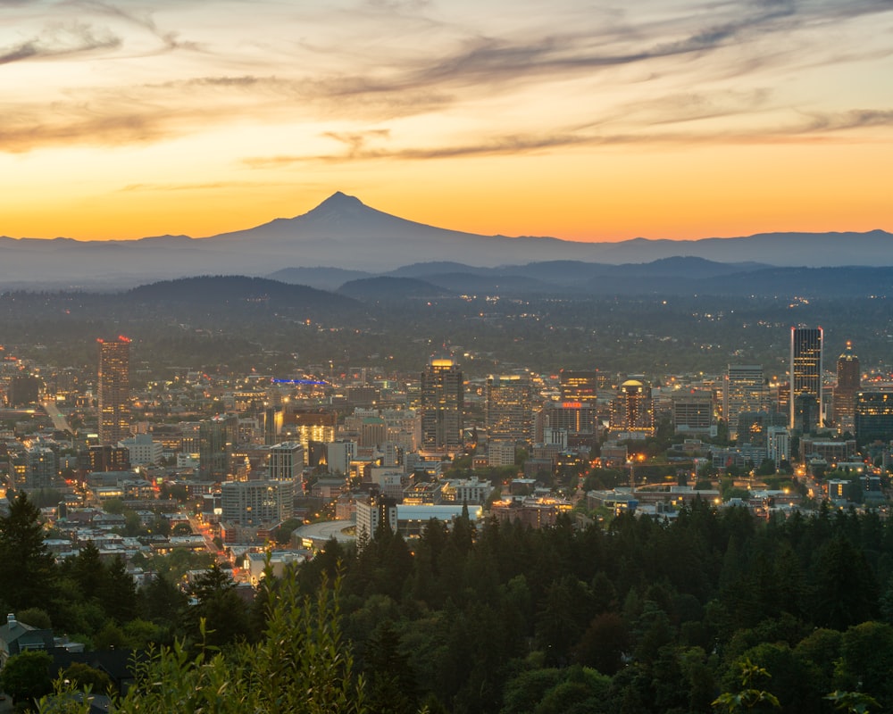 Stadt mit Hochhäusern in der Nähe von Bergen während des Sonnenuntergangs