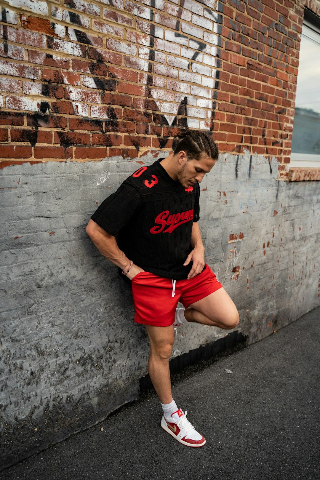 woman in black crew neck t-shirt and red shorts leaning on gray concrete wall during