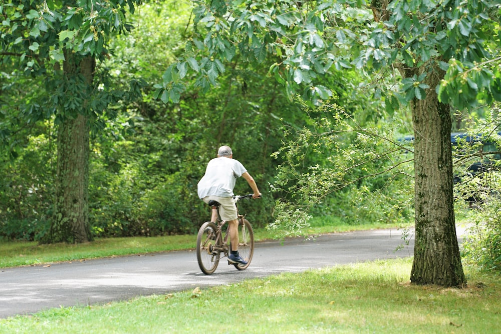 man in white t-shirt riding bicycle on road during daytime