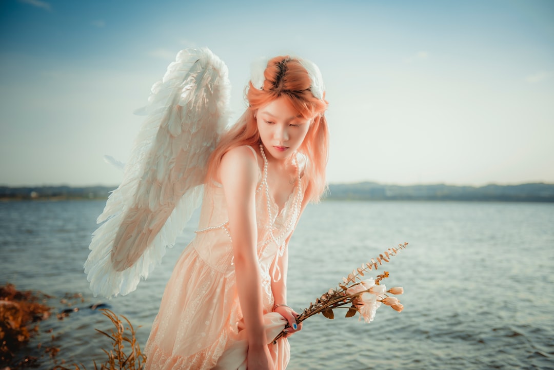 woman in pink dress holding white feather