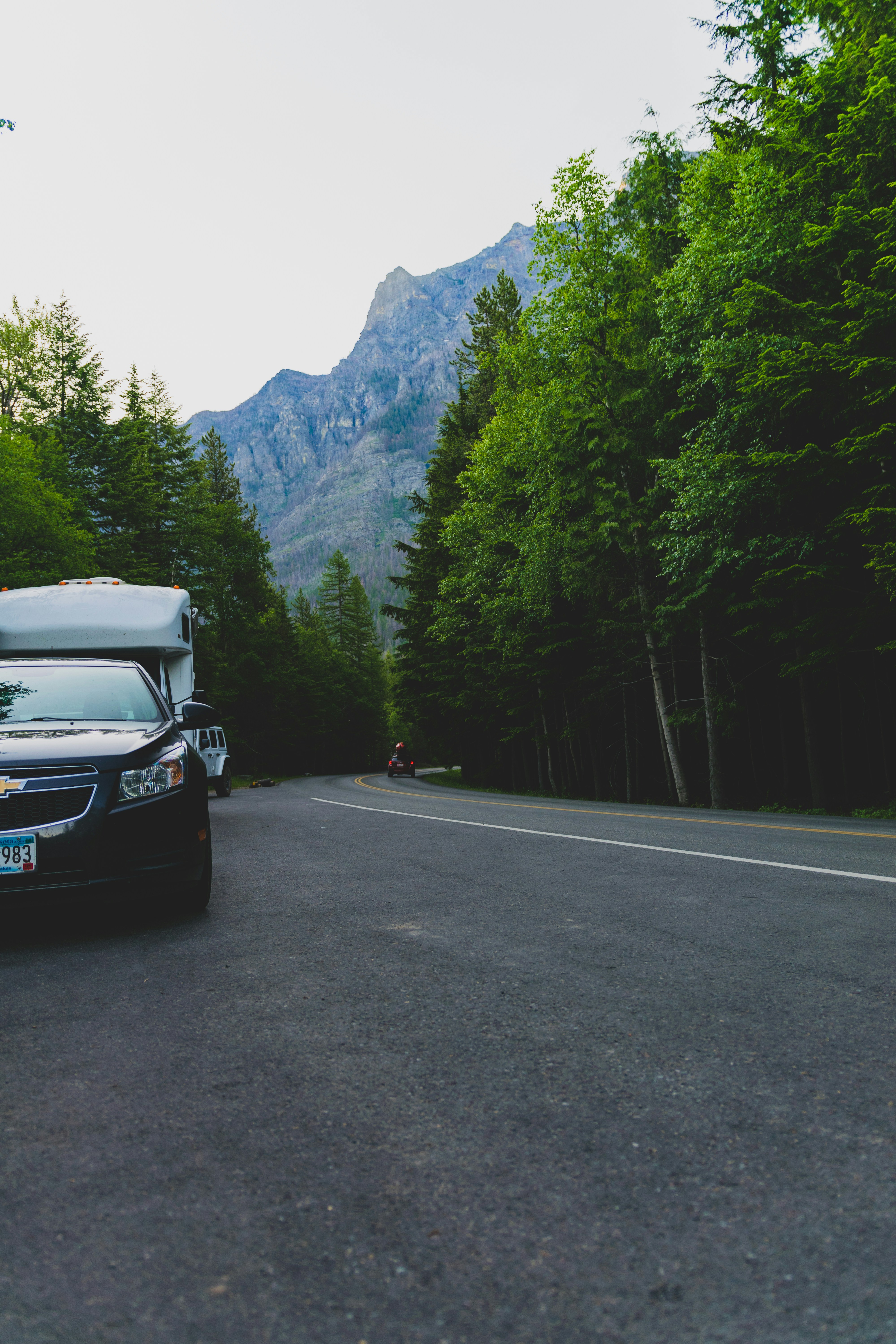 black car on road near green trees and mountain during daytime