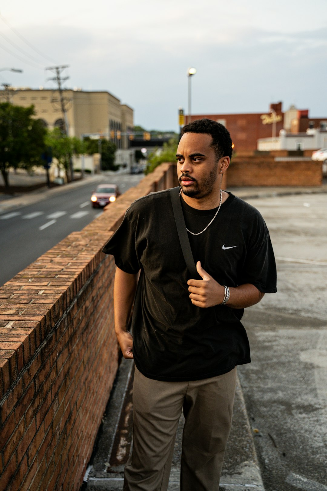 man in black crew neck t-shirt standing on sidewalk during daytime