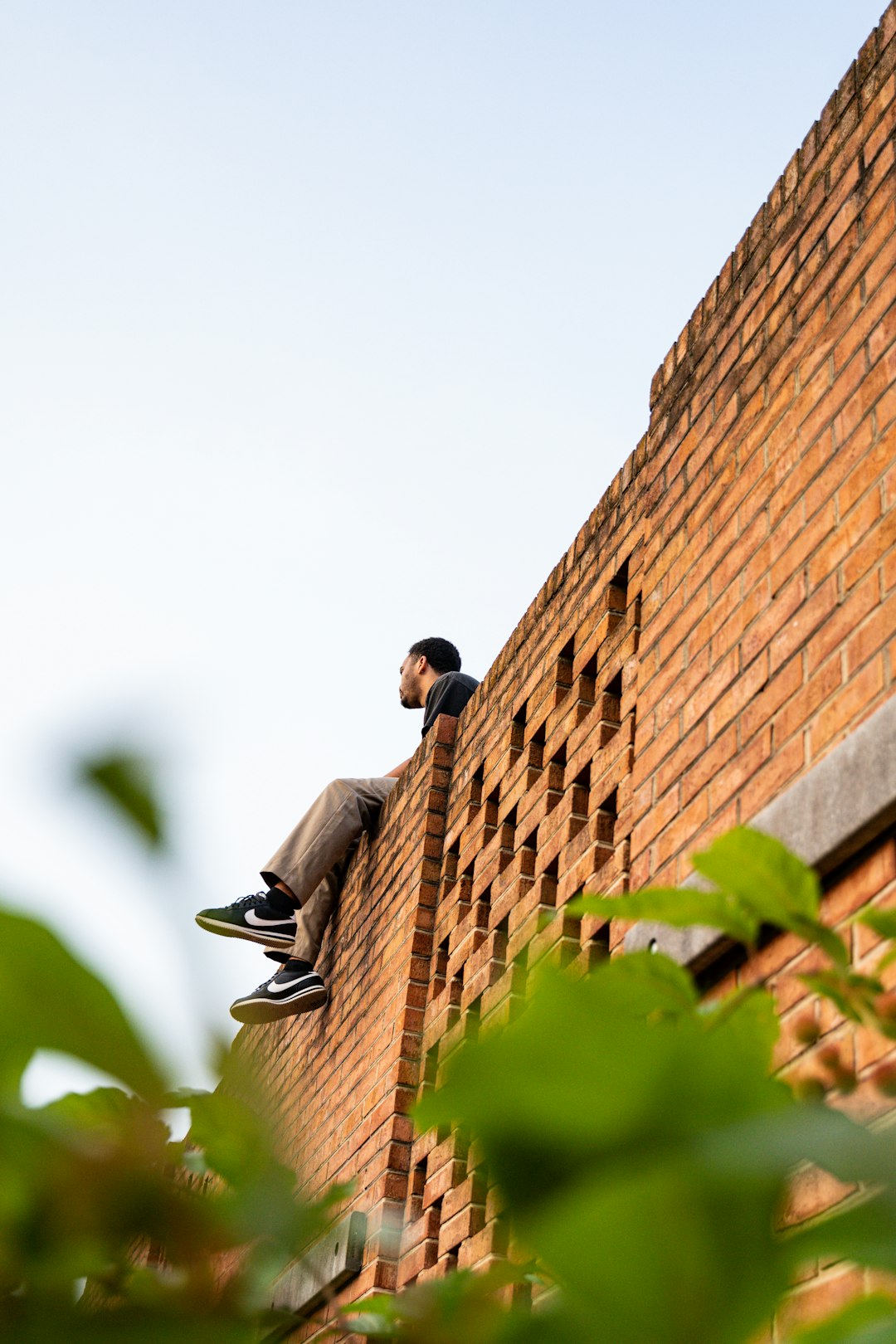 man in gray long sleeve shirt sitting on brown brick wall during daytime