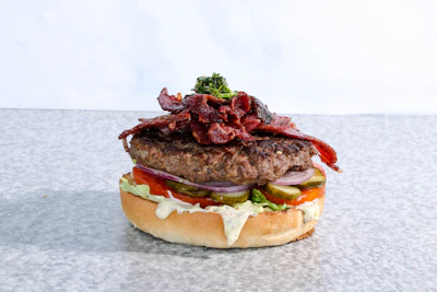 A gourmet burger stacked high with melted cheese, fresh lettuce, and crispy bacon.
