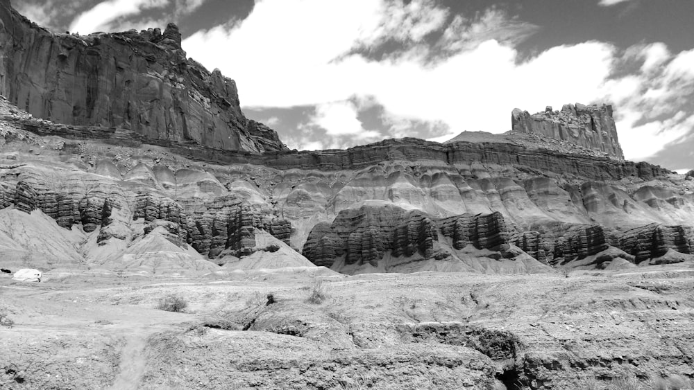 grayscale photo of rocky mountain under cloudy sky