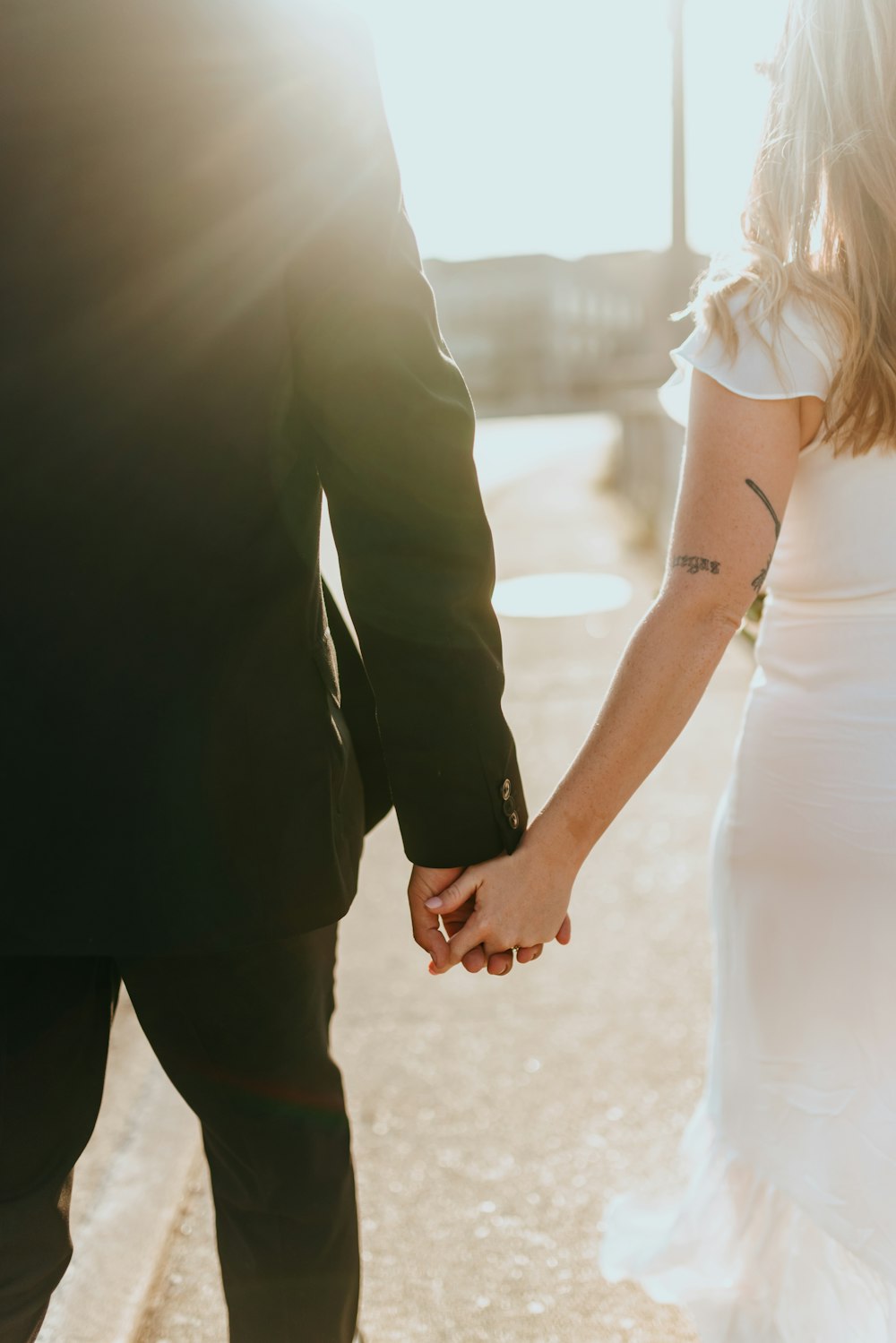 man in black pants holding woman in white dress