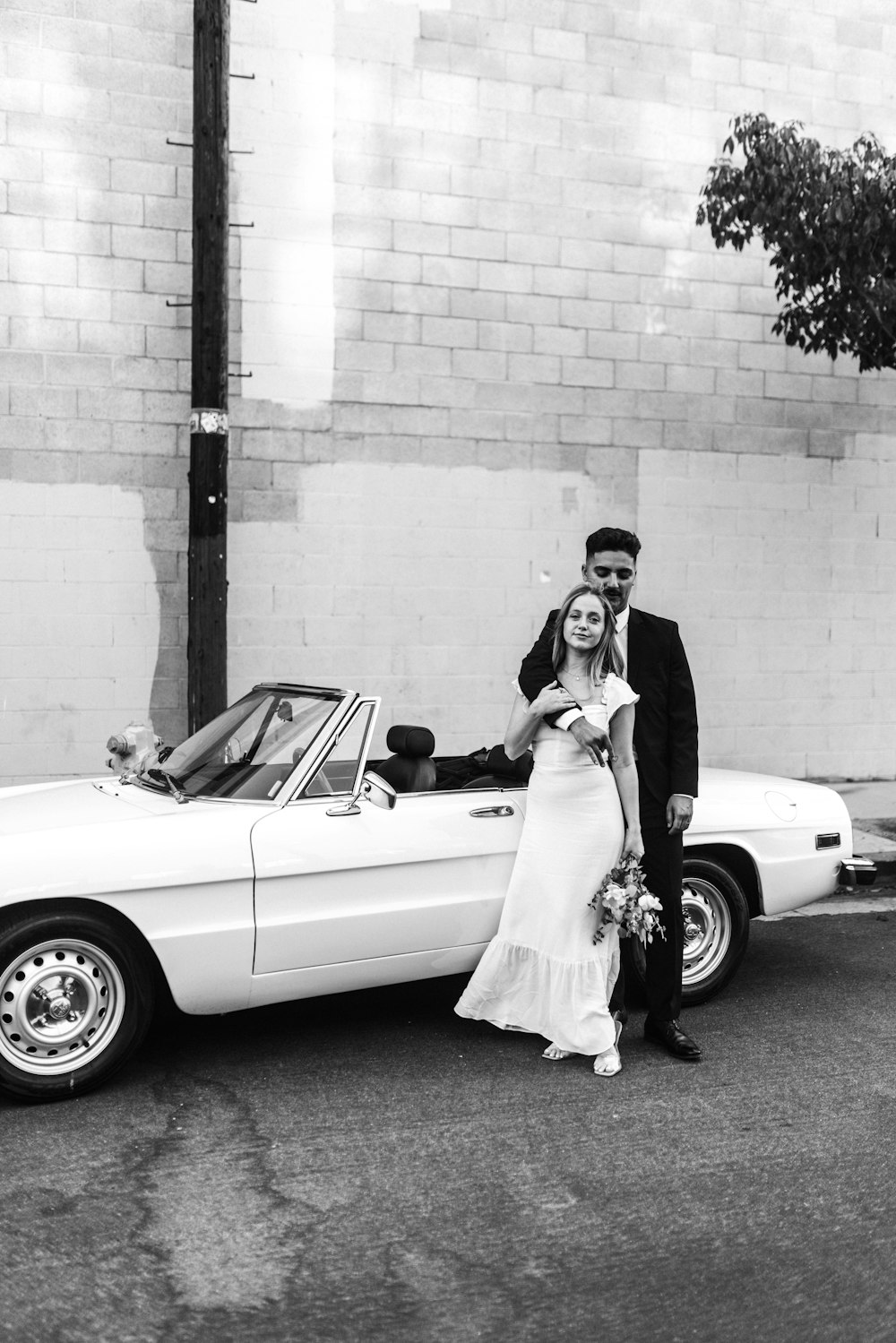 man and woman standing beside white convertible coupe
