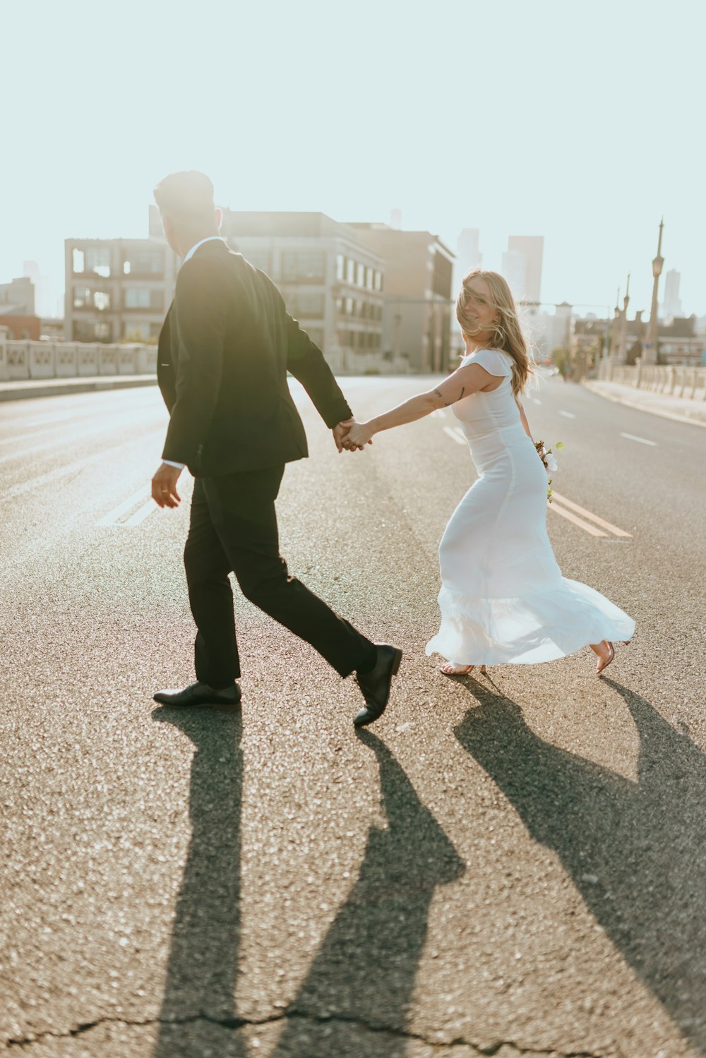 man in black suit holding woman in white dress walking on street during daytime