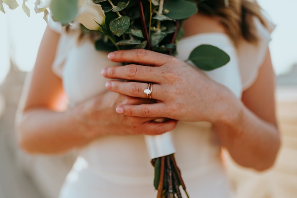 woman in white dress holding green plant