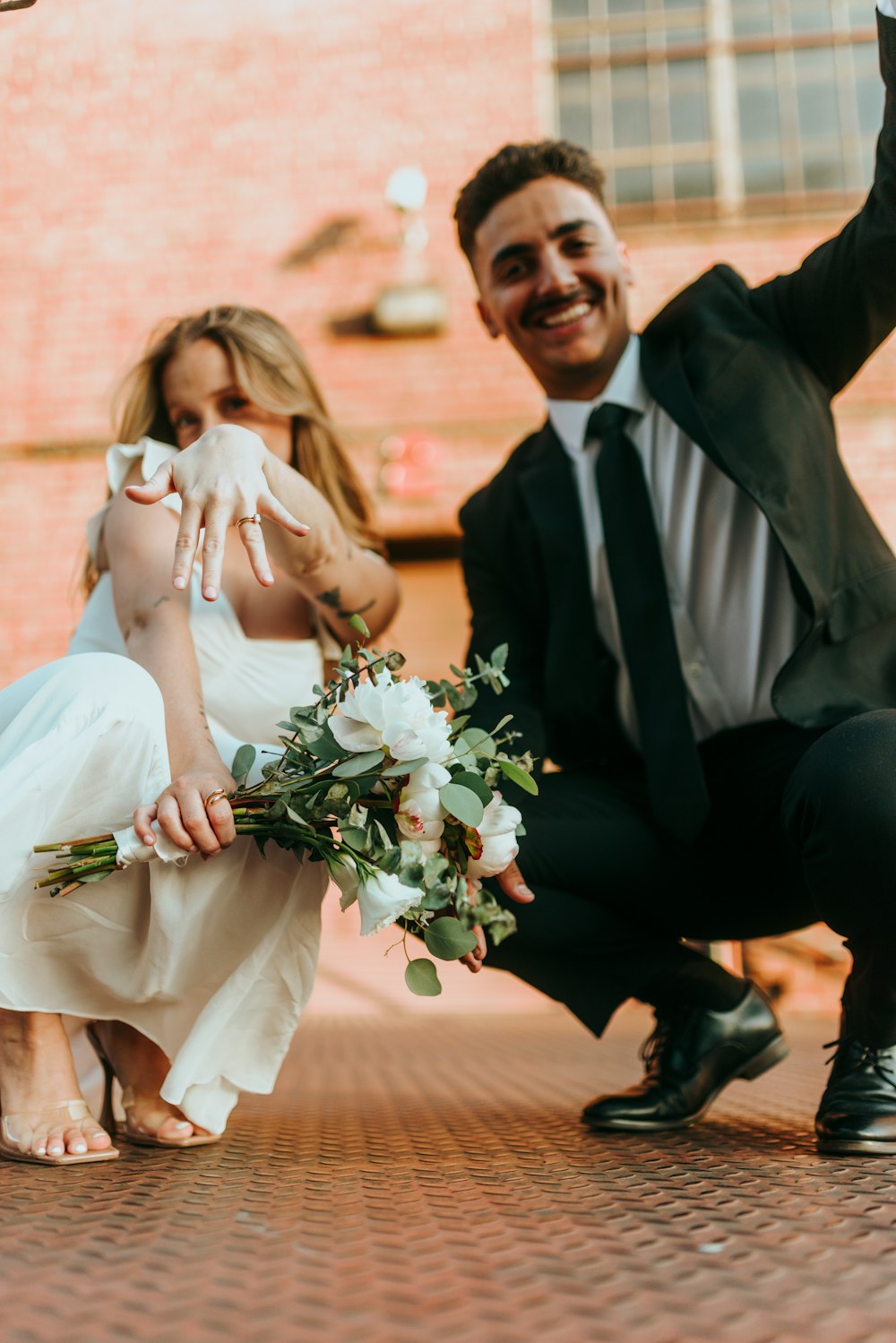 man in black suit jacket sitting beside woman in white wedding dress