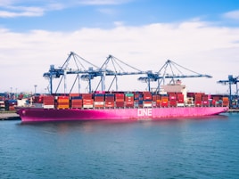 red cargo ship on sea under blue sky during daytime