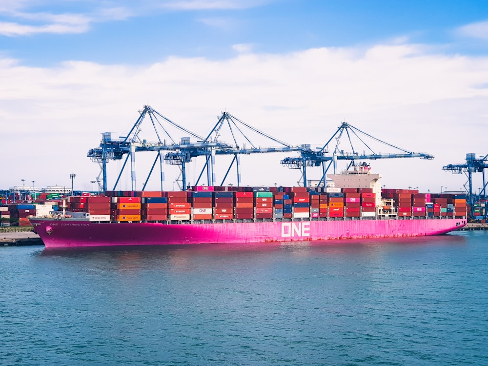 red cargo ship on sea under blue sky during daytime