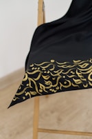 A beautifully stitched prayer shawl draped over a wooden chair, highlighting its soft organic fabric.