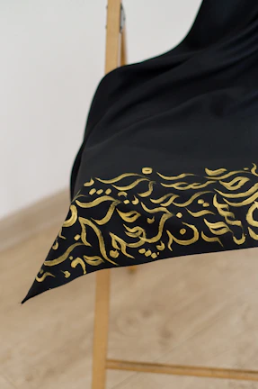 Traditional abaya with rich fabric and classic design, draped over a chair.