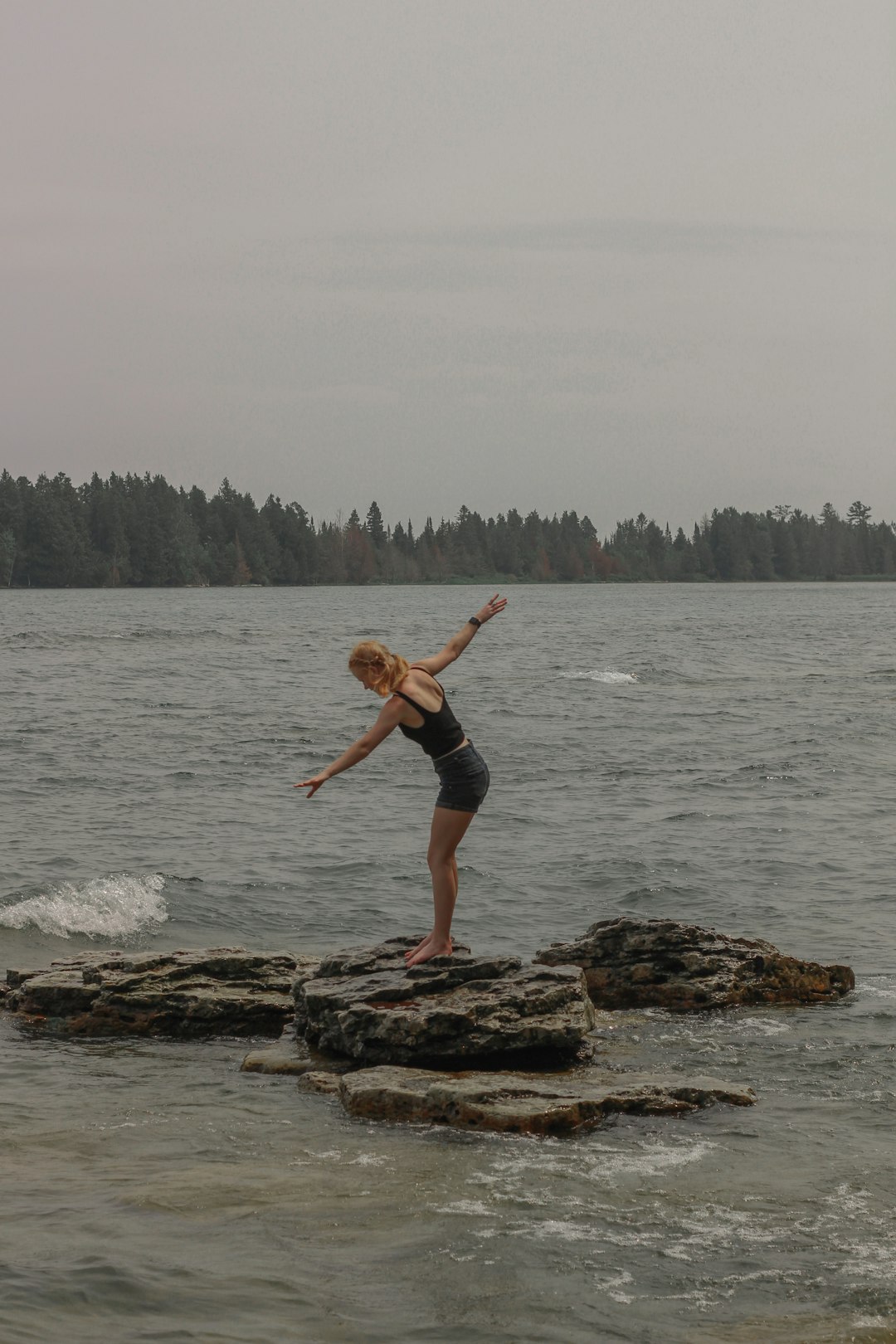 woman in black bikini standing on brown rock near body of water during daytime