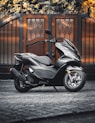 black and gray motor scooter parked beside brown brick wall