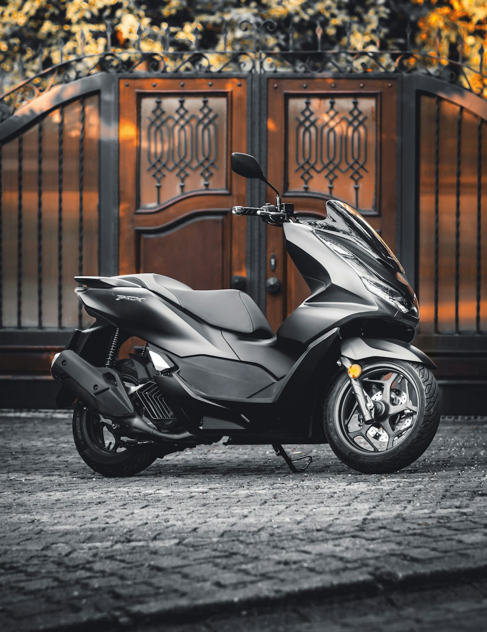 black and gray motor scooter parked beside brown brick wall