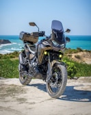 black and gray motorcycle on brown sand near body of water during daytime