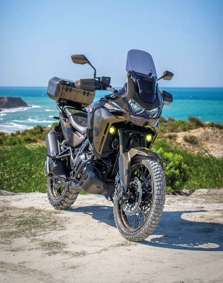 black and gray motorcycle on brown sand near body of water during daytime