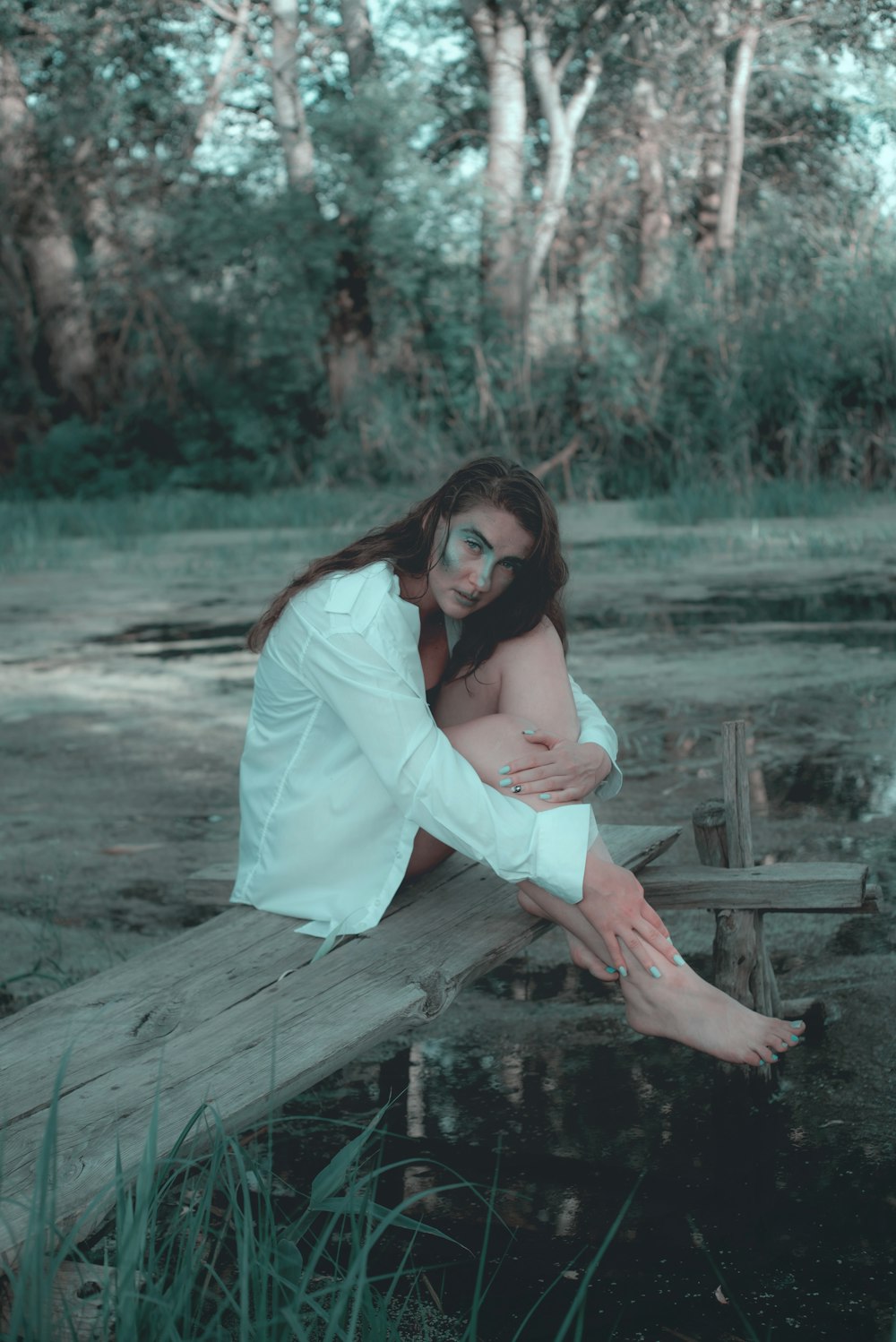 woman in white long sleeve shirt sitting on brown wooden dock