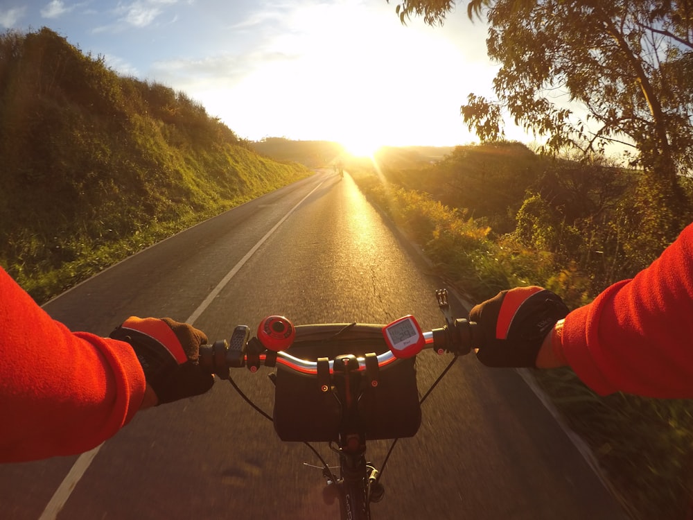 person in red jacket riding bicycle on road during daytime