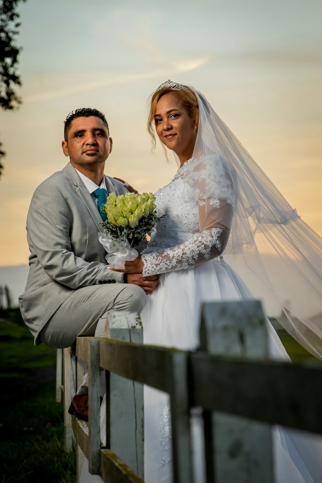man in gray suit jacket holding bouquet of flowers beside woman in white wedding gown