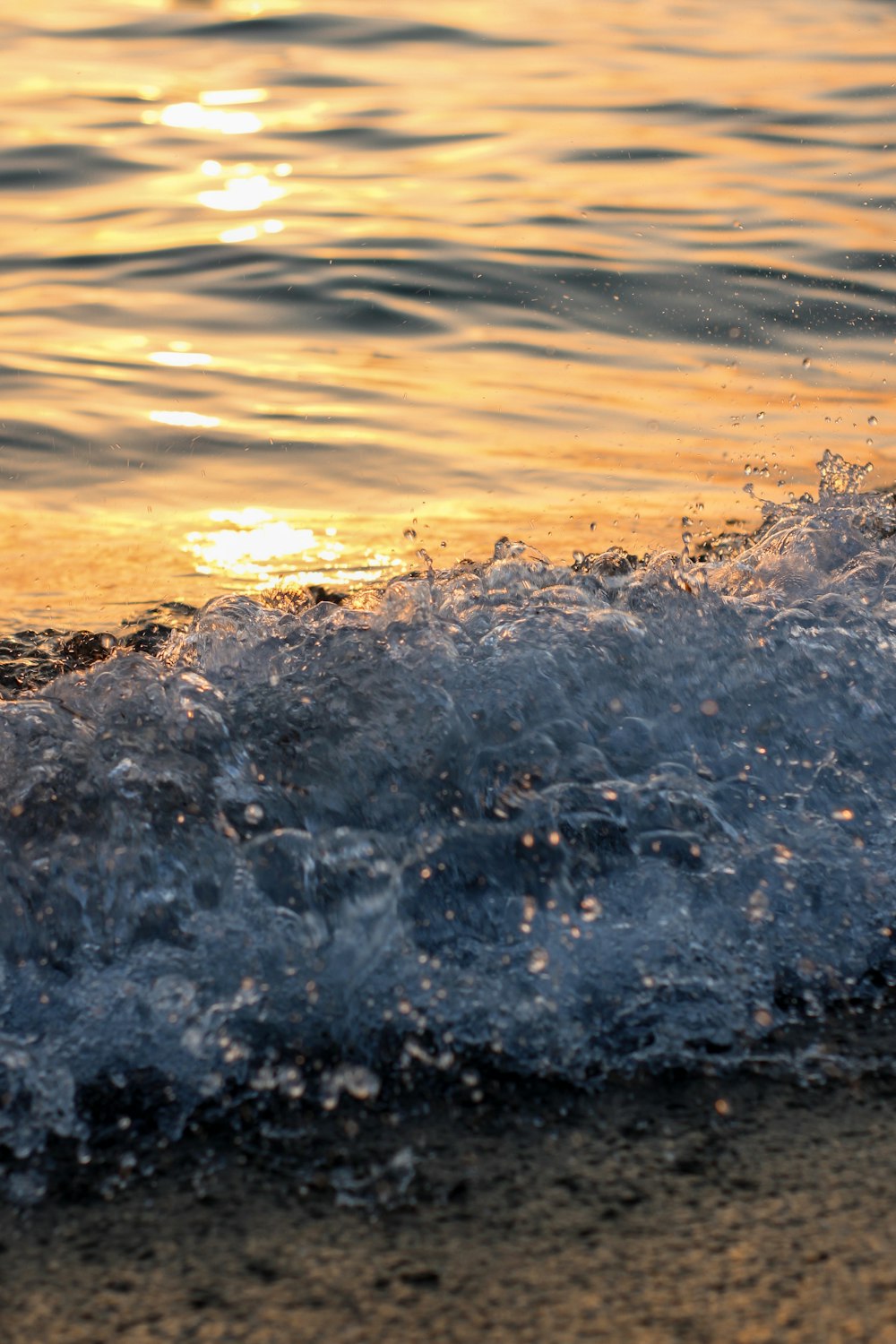 water waves on brown sand during sunset