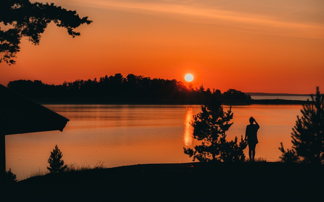 silhouette of people standing near body of water during sunset