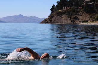 Athlete swimming in open water with a calm lake background