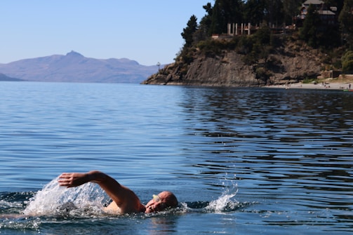 Athlete swimming in open water with a calm lake background